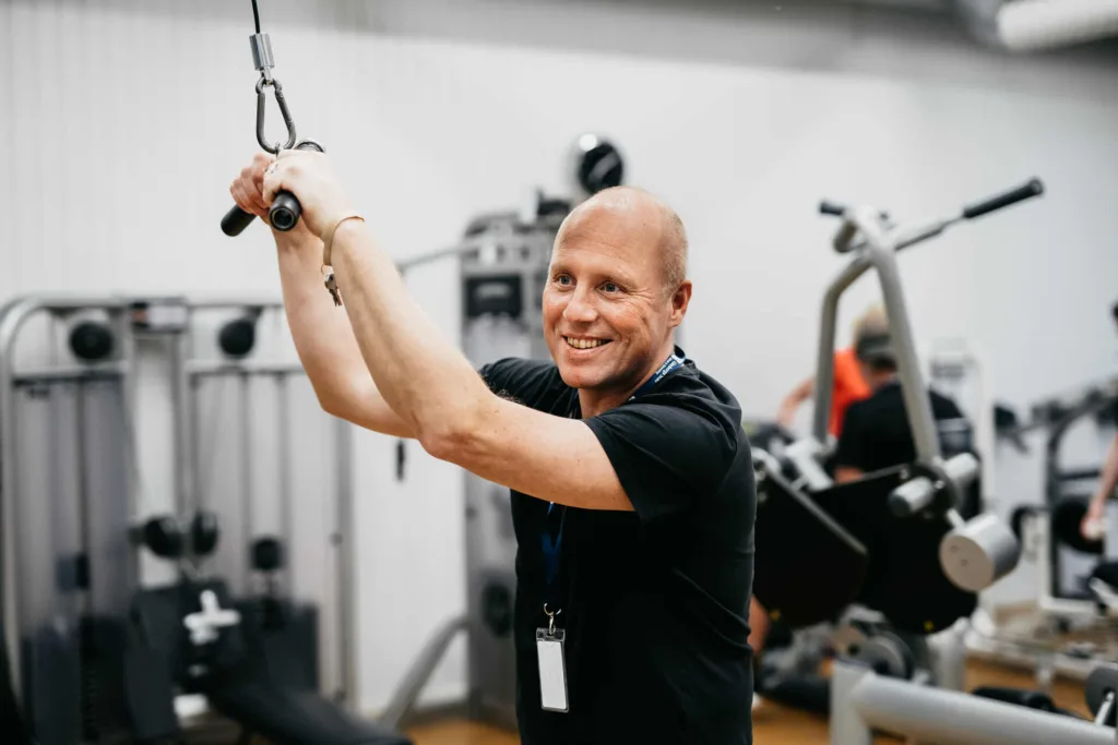 Räddningsmissionens personal är med och tränar i gymmet och ler